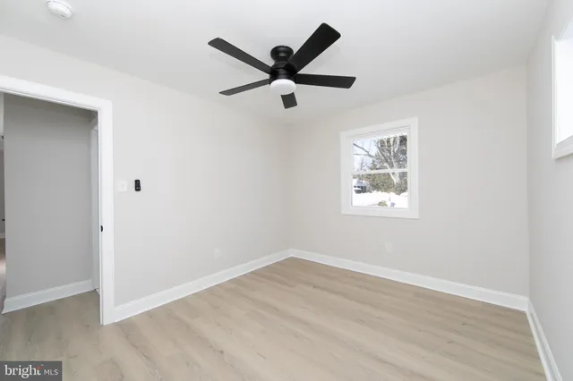 an empty room with wooden floor and ceiling fan