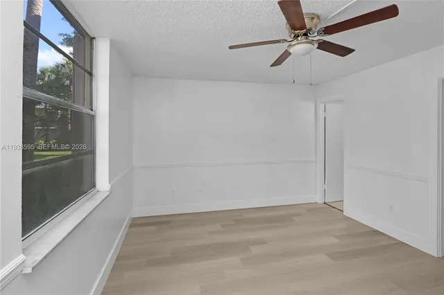 a view of empty room with wooden floor and fan