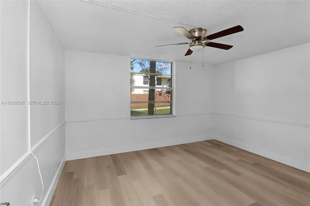 an empty room with a window and a ceiling fan