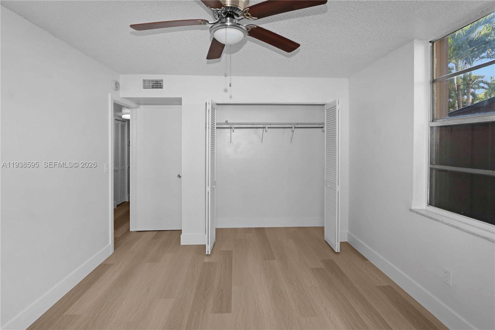 8309 Southwest 142nd Avenue, Unit G112 Miami, FL 33183 - Photo 16 of 28 an empty room with wooden floor closet and windows