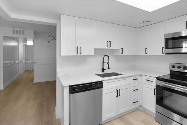 a kitchen with white cabinets stainless steel appliances and sink