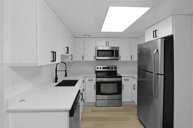 a kitchen with white cabinets stainless steel appliances and a refrigerator