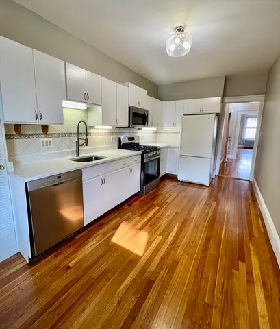 a kitchen with wooden floors and stainless steel appliances