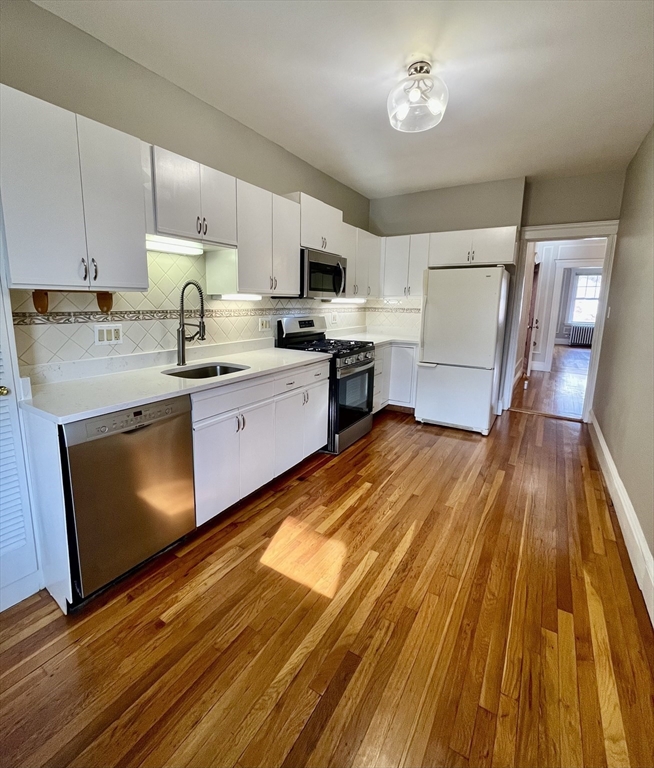 26 Gibbs Street, Unit 5 Brookline, MA 02446 - Photo 2 of 14 a kitchen with wooden floors and stainless steel appliances