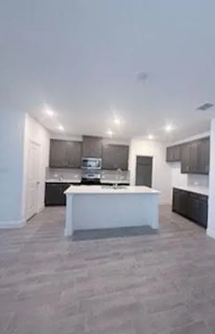 a large kitchen with kitchen island a sink a counter top stainless steel appliances and cabinets