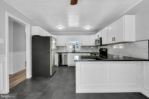 a kitchen with stainless steel appliances granite countertop a refrigerator a sink a stove a microwave and white cabinets