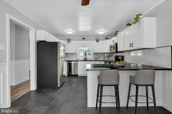 a kitchen with stainless steel appliances granite countertop a table chairs refrigerator and sink