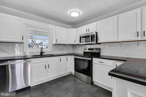 a kitchen with granite countertop white cabinets sink and stainless steel appliances