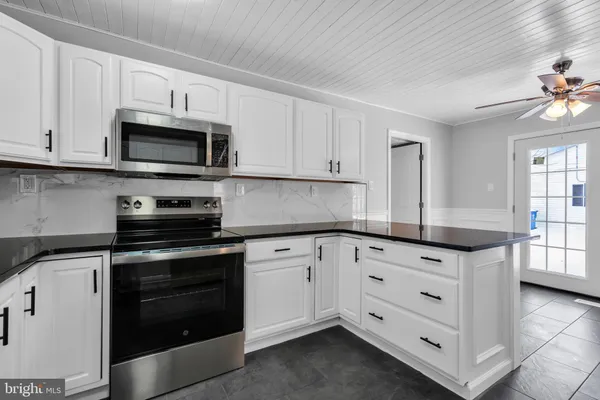 a kitchen with granite countertop white cabinets and stainless steel appliances