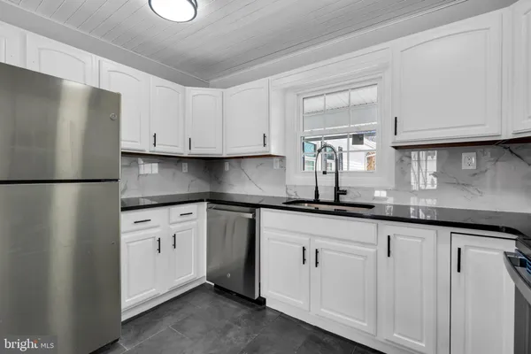 a kitchen with granite countertop white cabinets white appliances and a sink