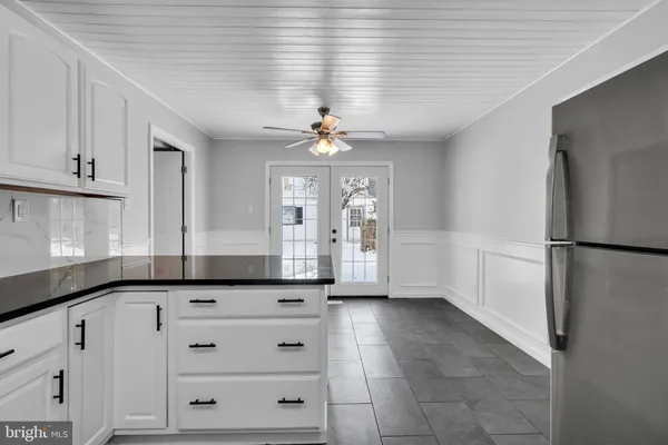 a kitchen with granite countertop white cabinets and refrigerator