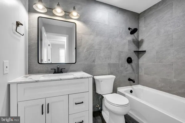 a bathroom with a granite countertop toilet a sink a mirror and bathtub