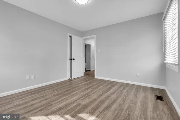 a view of an empty room with wooden floor and window