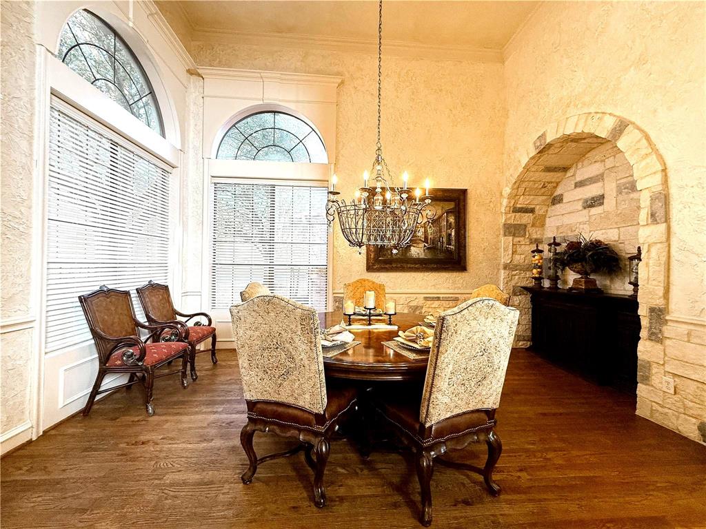 1919 Kings Pass Heath, TX 75032 - Photo 8 of 38 Dining area featuring hardwood floors, a stone archway, tall arched windows, and an ornate chandelier