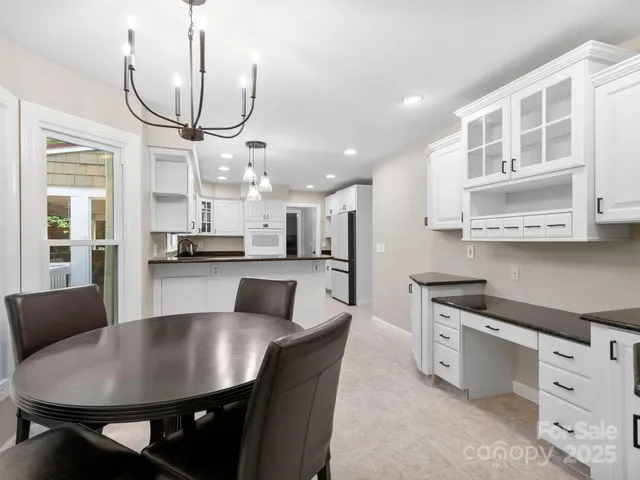 a kitchen with granite countertop a table chairs stove and cabinets