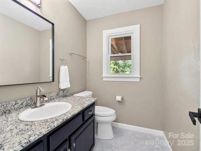 a bathroom with a granite countertop toilet a sink and a mirror