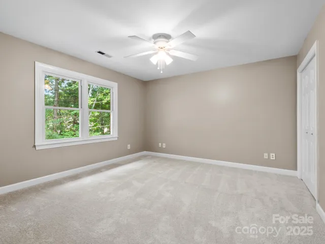 an empty room with windows and chandelier fan