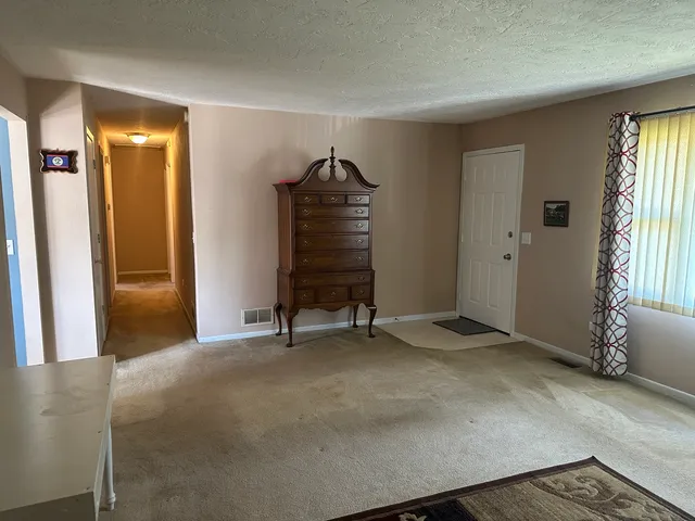 a view of an empty room with a fireplace and a window