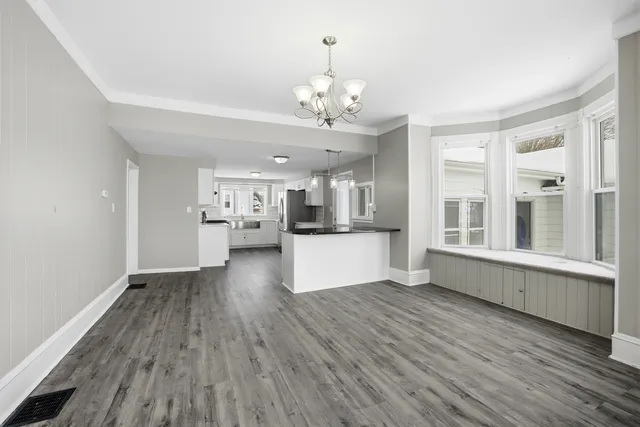 a view of an empty room with kitchen and window