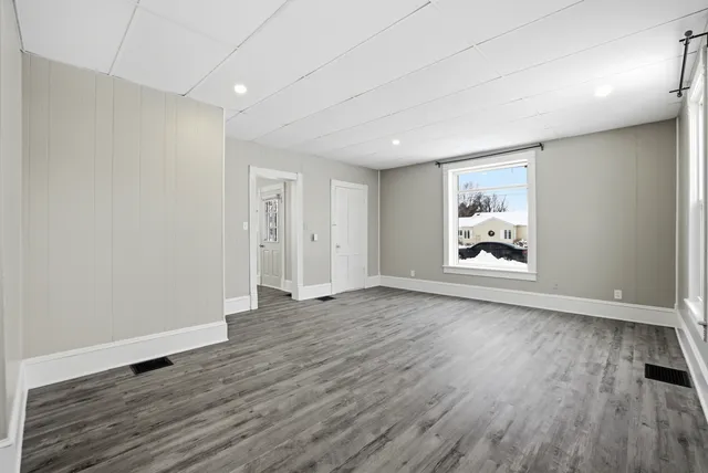 an empty room with wooden floor and window