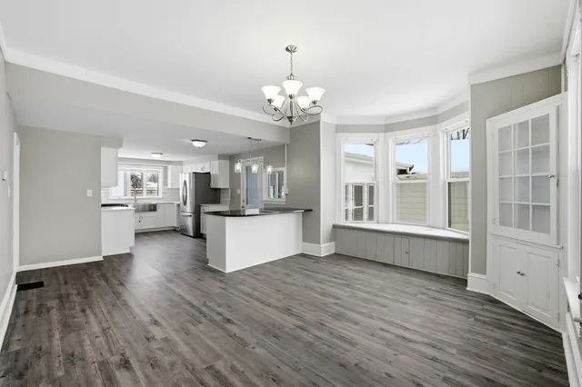 a view of a kitchen with kitchen island granite countertop wooden floor and stainless steel appliances