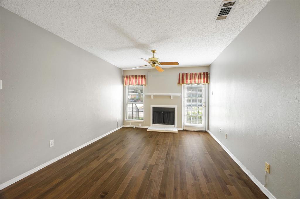 18333 Roehampton Drive, Unit 1412 Dallas, TX 75252 - Photo 3 of 14 a view of an empty room with wooden floor fireplace and a window