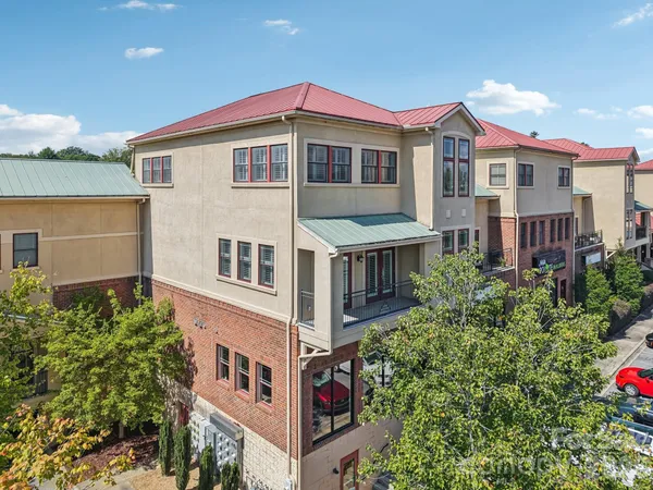 a front view of residential houses with yard and car parked