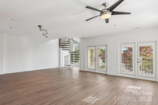 an empty room with wooden floor closet and windows