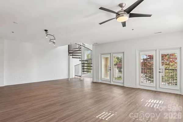 an empty room with wooden floor closet and windows