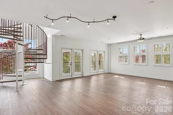 a view of an empty room with wooden floor and windows