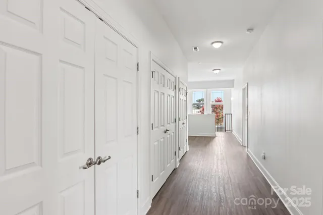 a view of a hallway with wooden floor and closet area