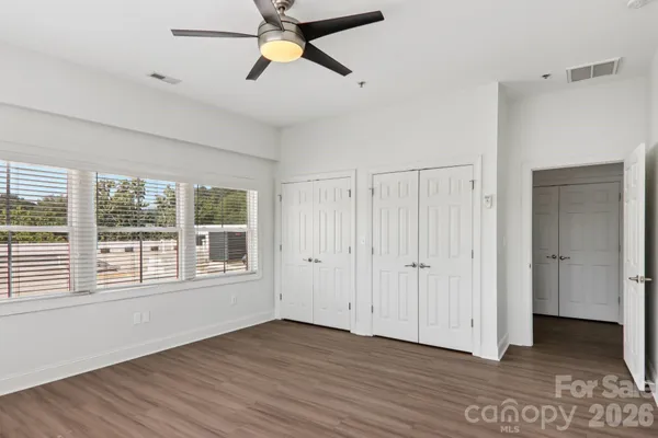 a view of empty room with wooden floor and fan