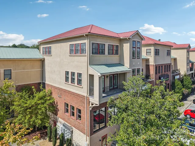 a front view of residential houses with yard and car parked