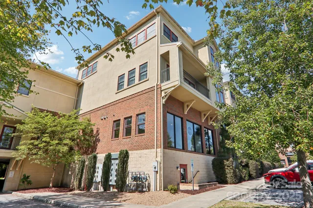 a view of a white building among the street with palm trees