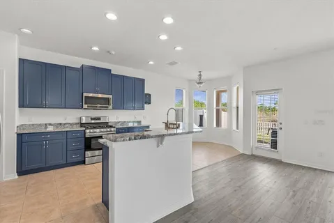 a large kitchen with stainless steel appliances granite countertop a stove top oven a sink dishwasher and a refrigerator with wooden floor