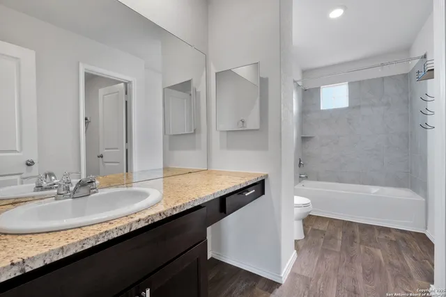 a bathroom with a granite countertop sink a toilet and shower