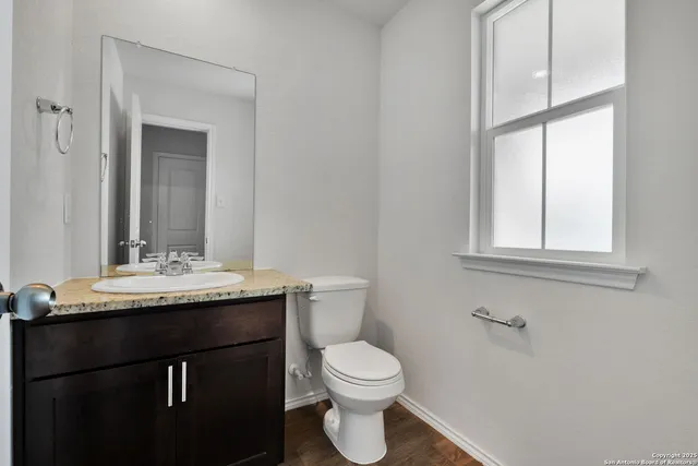 a bathroom with a granite countertop sink a toilet and a mirror