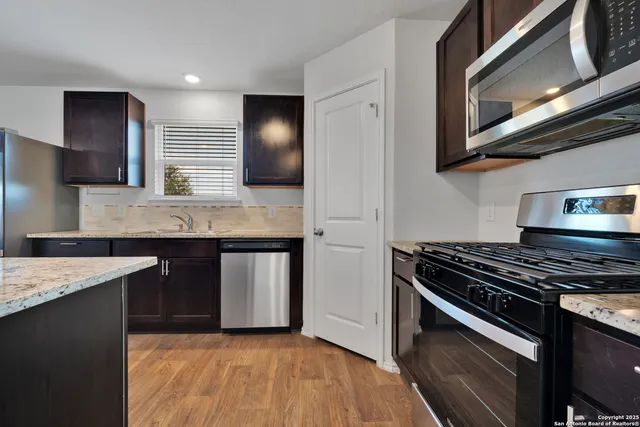 a kitchen with stainless steel appliances granite countertop a stove a sink and a microwave