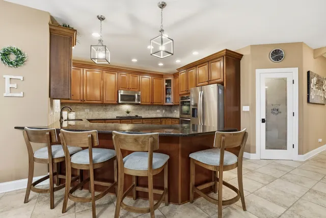 a kitchen with stainless steel appliances granite countertop a table chairs refrigerator and microwave