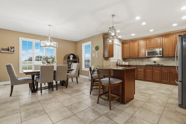 a kitchen with kitchen island granite countertop wooden cabinets a dining table and chairs