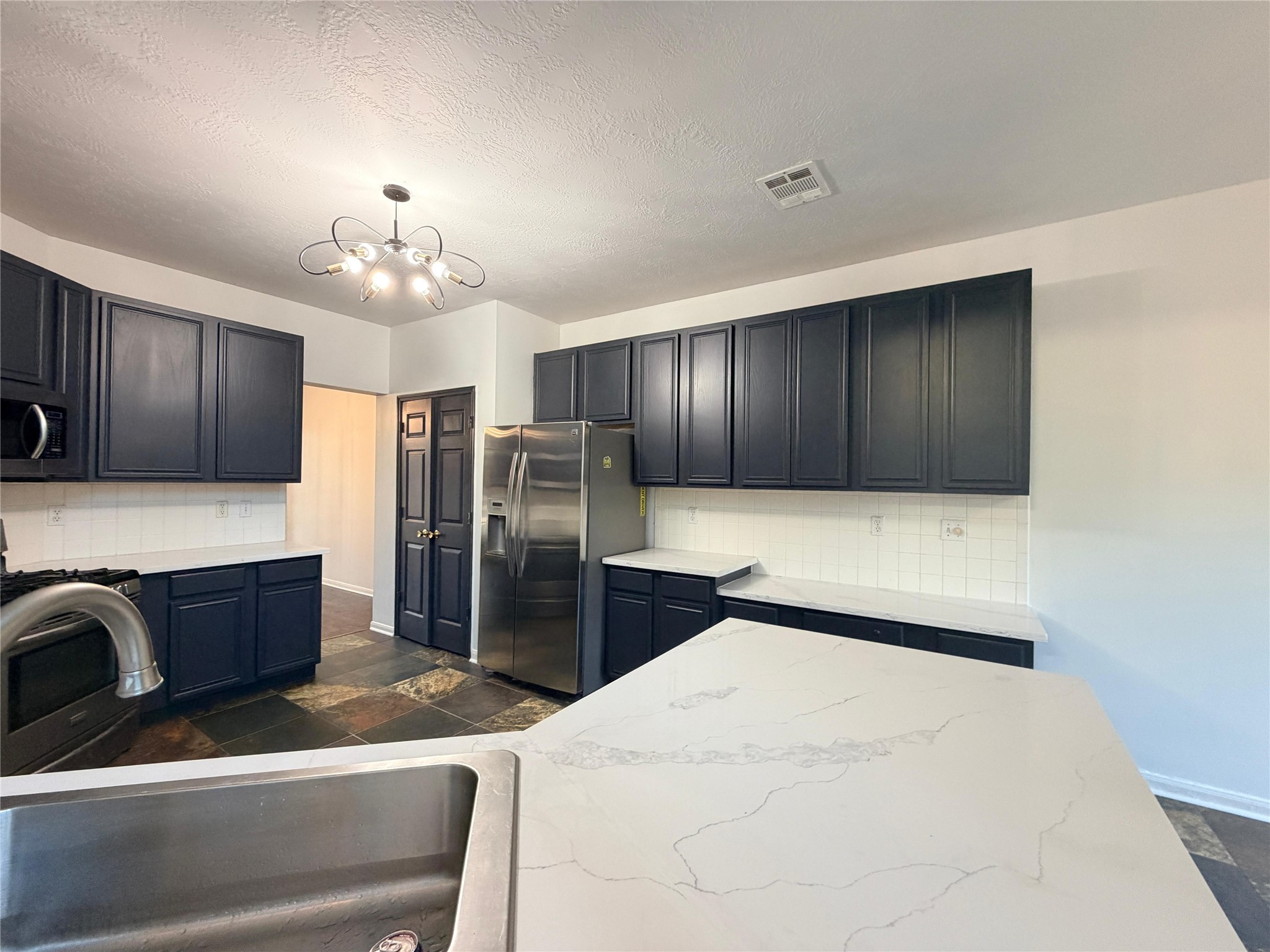 13002 Bainbridge Trail Houston, TX 77065 - Photo 12 of 32 a large kitchen with stainless steel appliances kitchen island granite countertop a refrigerator a stove and a sink with wooden cabinets