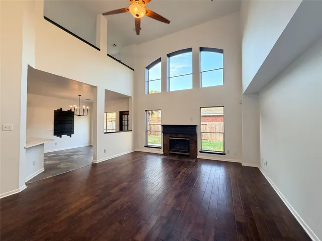 an empty room with wooden floor fireplace and windows