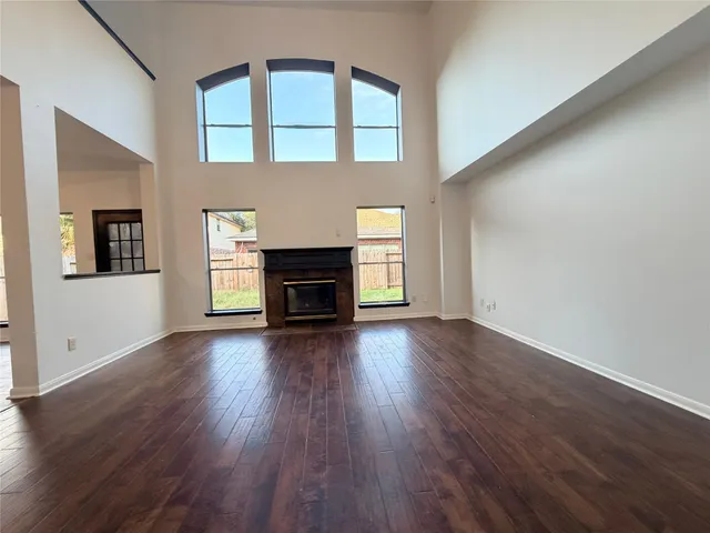 a view of an empty room with wooden floor fireplace and a window