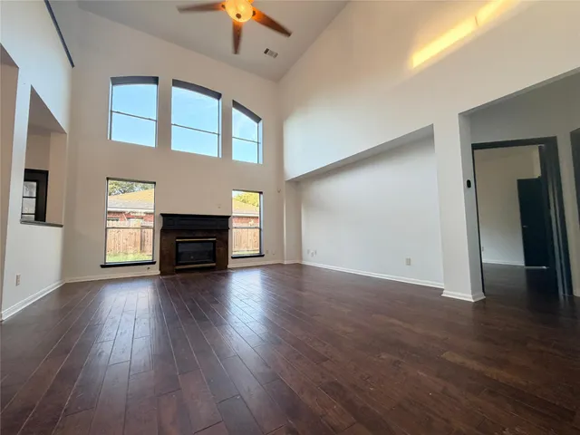 an empty room with wooden floor fireplace and windows