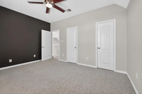an empty room with a ceiling fan and carpet