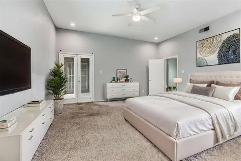 a spacious bedroom with a bed and a flat screen television