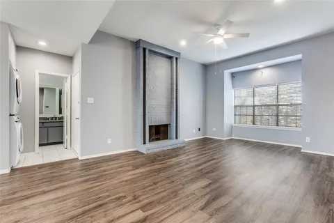 an empty room with wooden floor chandelier and windows