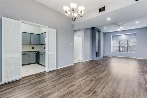 a view of an empty room with kitchen and window