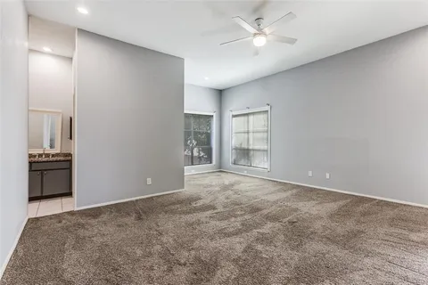 a view of an empty room with a ceiling fan and window