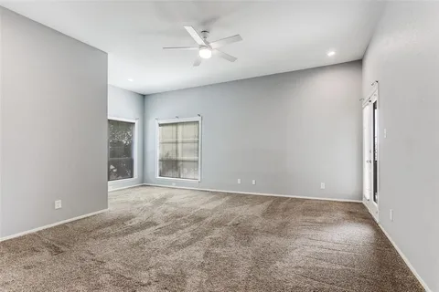 an empty room with windows and ceiling fan